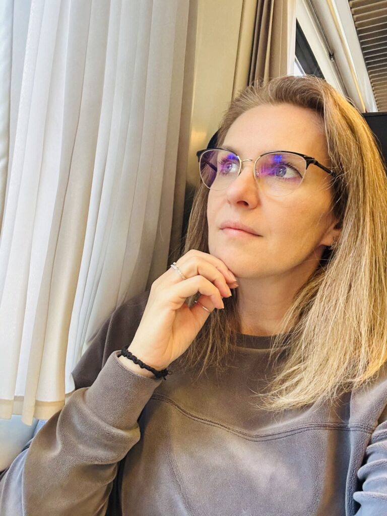 Lenka Tarpataki v&nbsp;domácím prostředí se zamyšleně dívá z&nbsp;okna. Fotografie vyjadřuje zastavení a&nbsp;přemýšlení o&nbsp;práci.